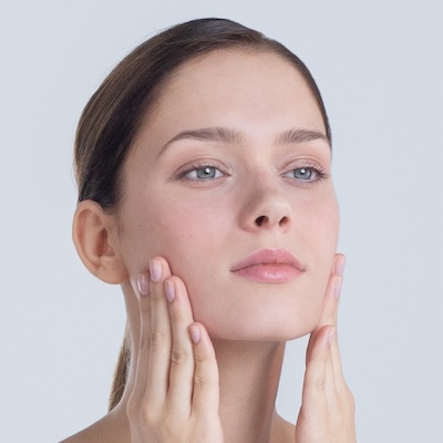 Modelo ESTHEDERM con piel saludable tocando suavemente su rostro