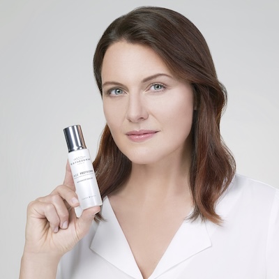 Mujer sosteniendo Age Proteom™ Sérum de Longevidad Celular de Institut Esthederm, mostrando el producto protagonista de la rutina cronobiológica.