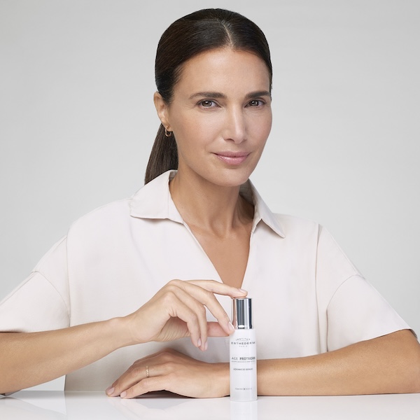 Mujer de piel luminosa sosteniendo el sérum AGE