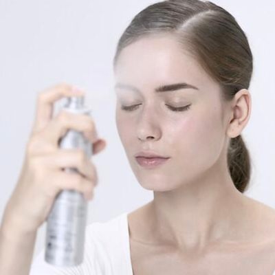 Bruma de Agua Celular: hidratación y frescura inmediata para la piel. Mujer aplicando bruma facial hidratante Eau Cellulaire de Institut Esthederm.